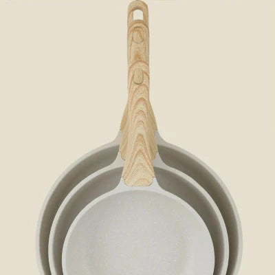 Trois poêles woks en céramique blanche de différentes tailles emboîtées, avec des manches en bois effet naturel