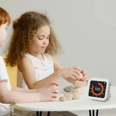 Changez-le pour : "Enfant utilisant la minuterie ChronoZen blanche pour gérer son temps de jeu avec des cubes en bois."